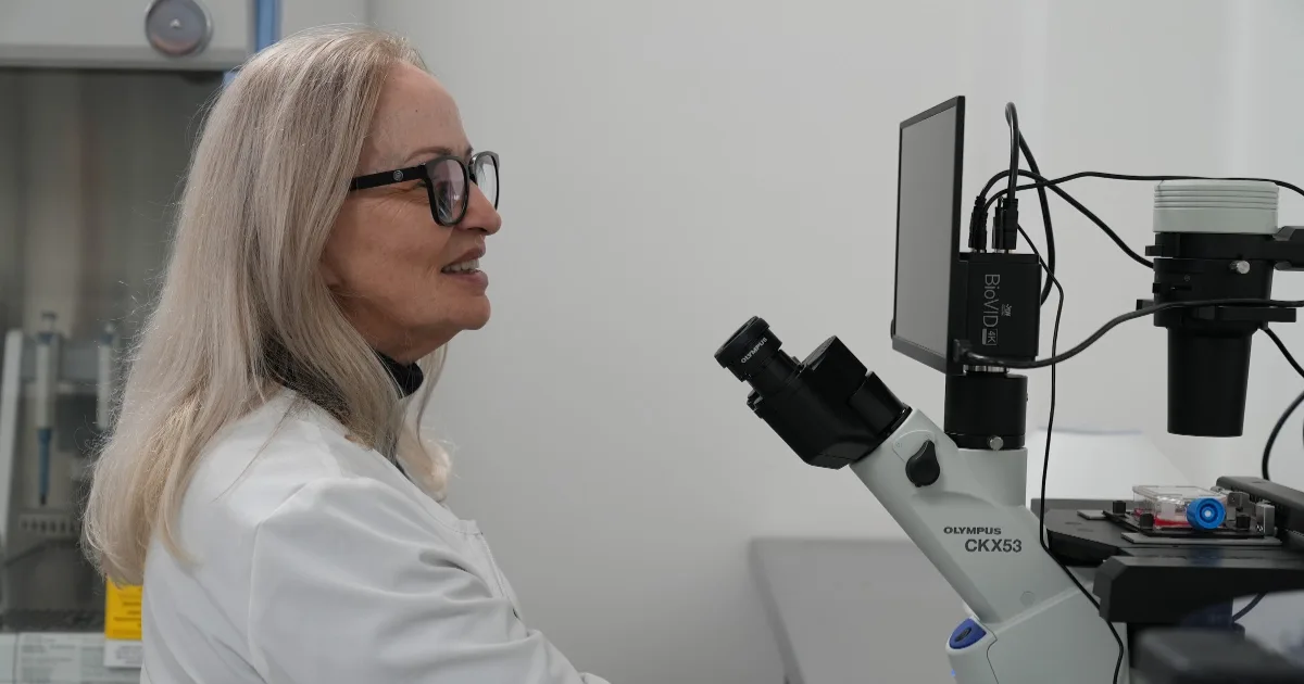 Scientist examining cell cultures under a microscope in the Blast Institute laboratory